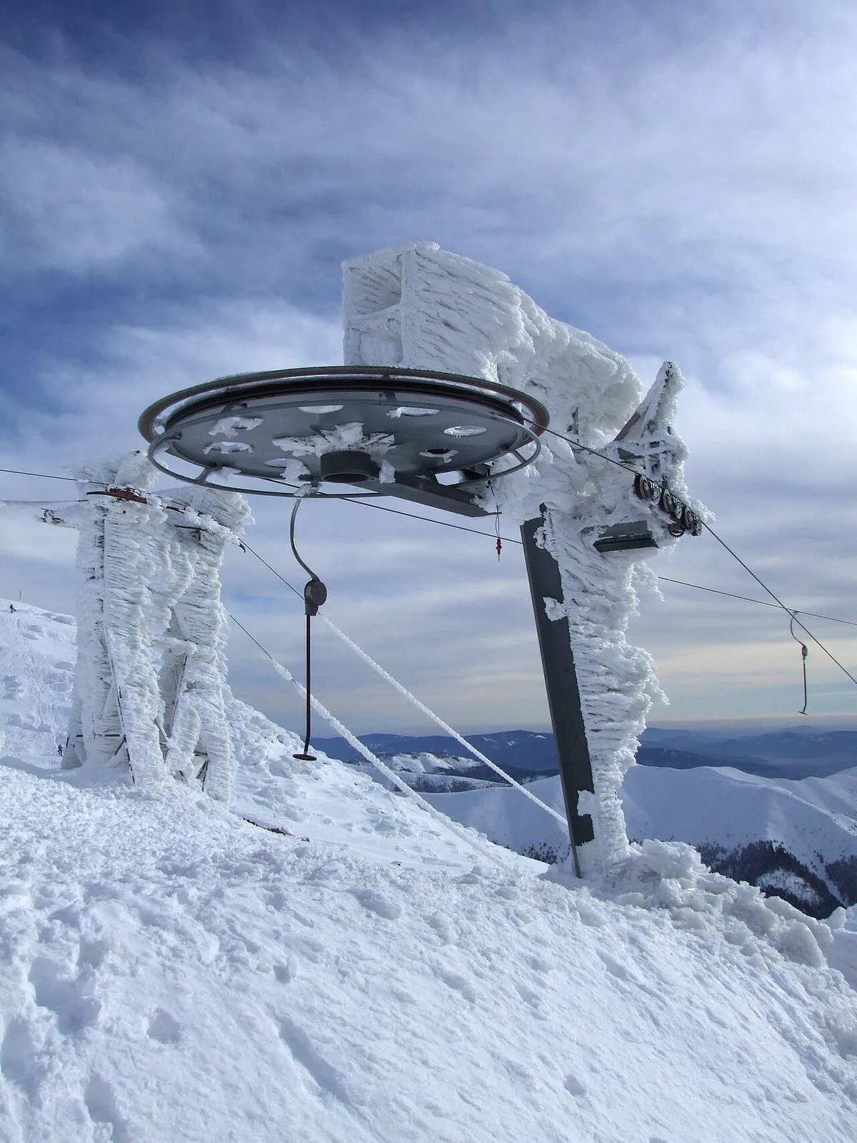 Een skilift op de Chopok in het gebied Jasná, met besneeuwde pistes en skiërs op de helling eronder.